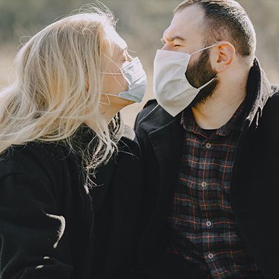 Photo of a couple kissing whilst wearing masks