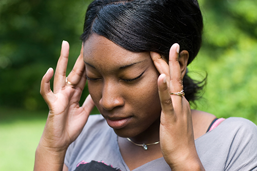 This young woman is experiencing intense stress or pain from a splitting headache.
