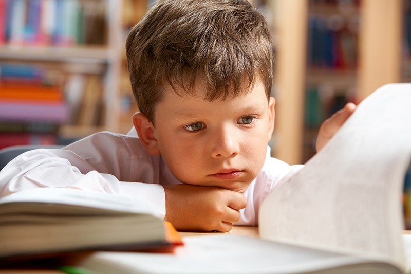 Close-up of boy preparing for lesson in library