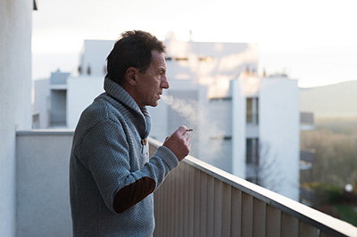 Man standing on balcony smoking