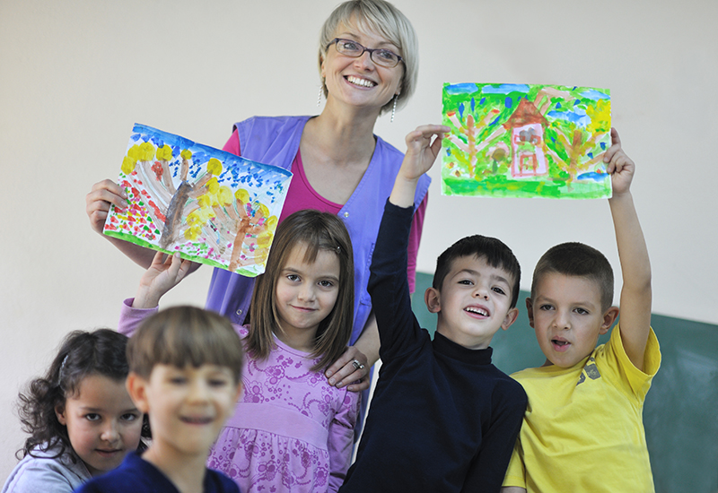 School children showing their drawings with their teacher
